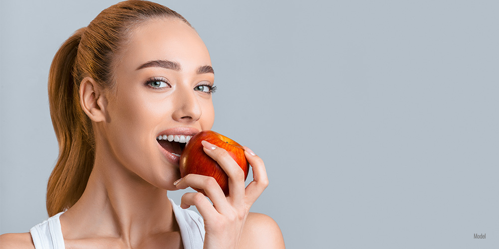 Female with healthy smile eating apple