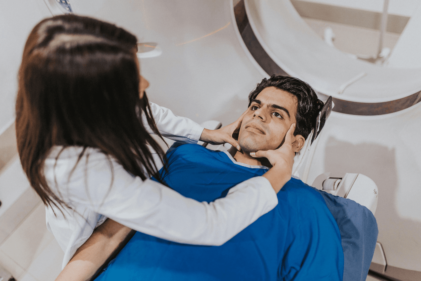 Patient undergoing MRI scan with dental crowns while technician positions head safely